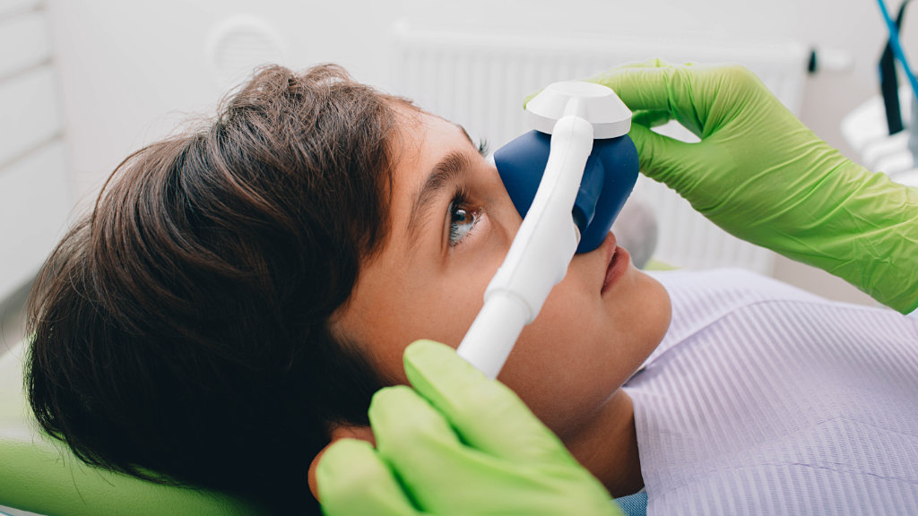 Young patient undergoing nitrous oxide sedation in dental chair