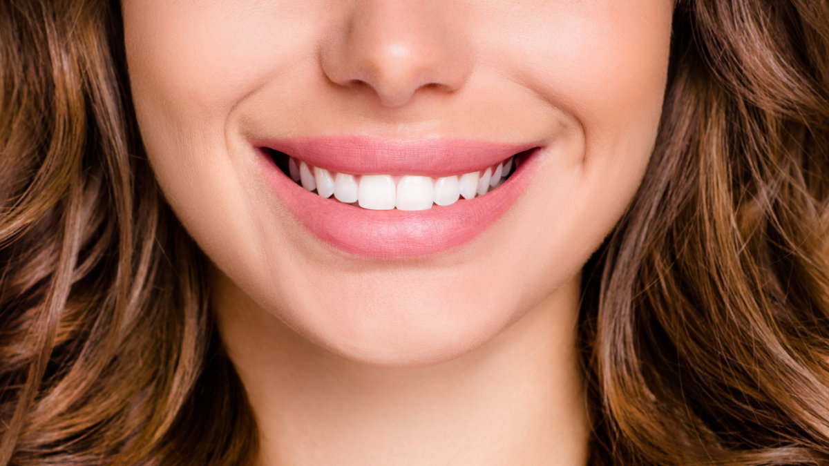 Close-up of woman smiling, showing straight teeth after orthodontic treatment