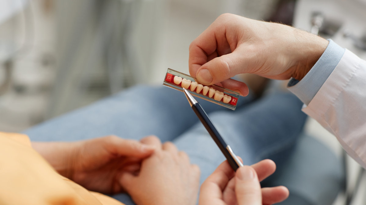 Close-up of dentist holding tooth models to explain crown lengthening procedure