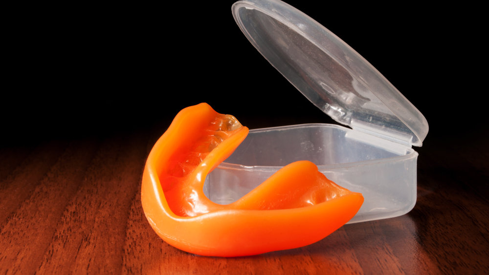 Close-up of orange mouthguard near opened case