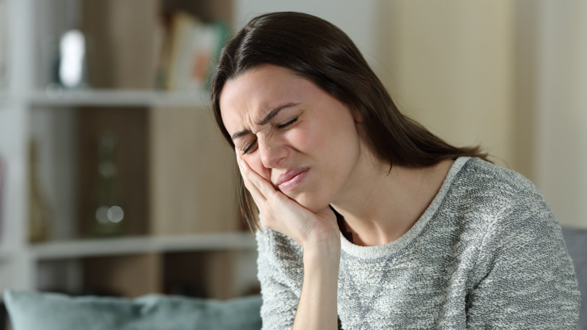 Woman holding cheek experiencing tooth pain